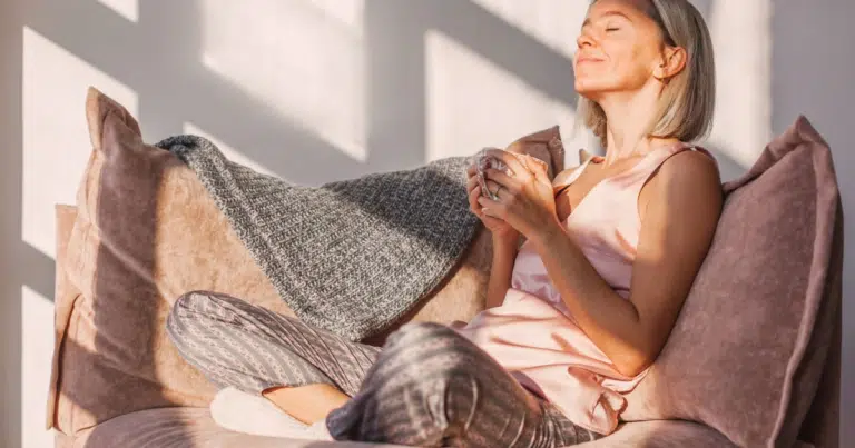 Woman relaxing comfortably on a couch in warm sunlight.